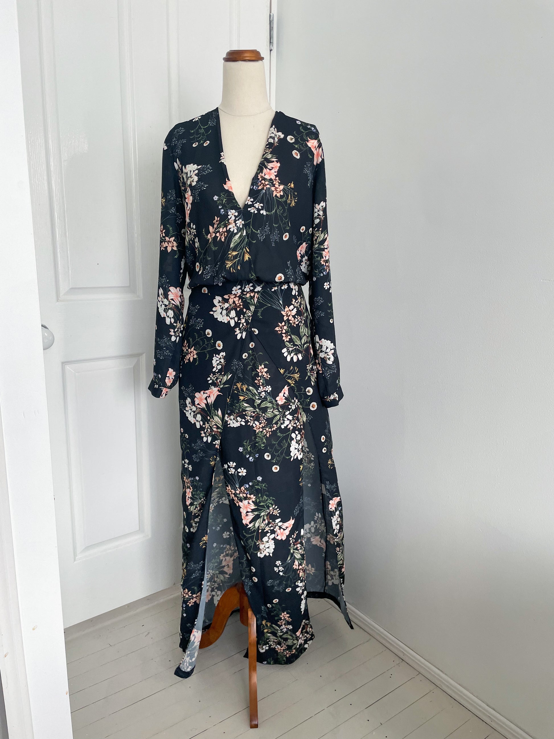 Sheike Midnight blooms dress. A long sleeve dress with plunging neck line and two front slits. the colour of the dress is pastel floral pattern on a dark fabric