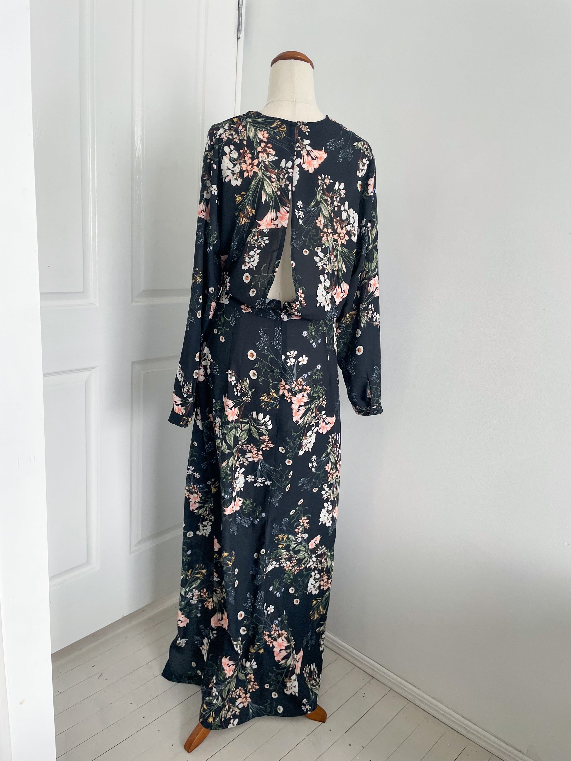 back view Sheike Midnight blooms dress. A long sleeve dress with plunging neck line and two front slits. the colour of the dress is pastel floral pattern on a dark fabric