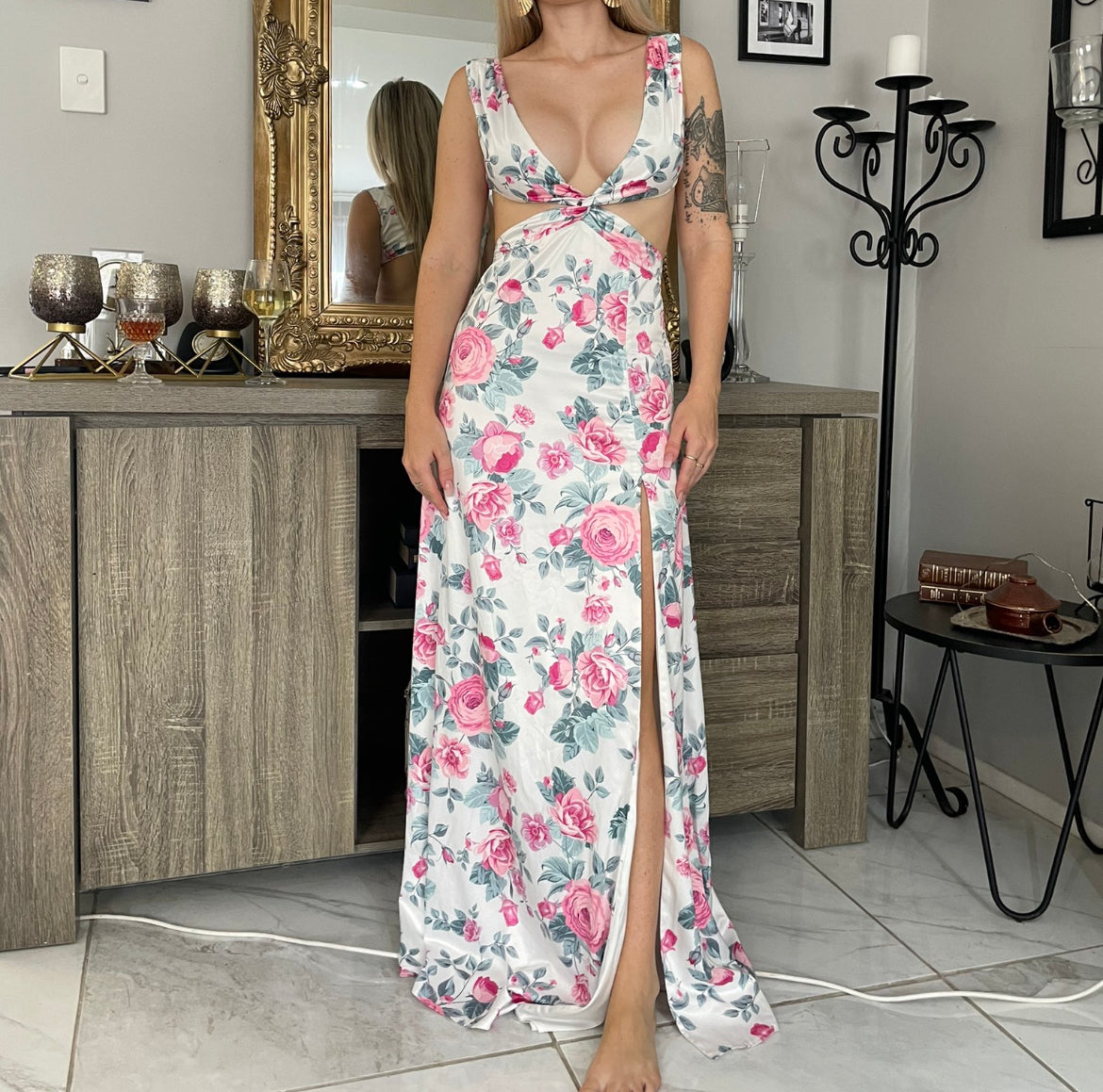 Model wearing long floral cutout maxi dress with front leg split. colours are pink flower with sage leaves