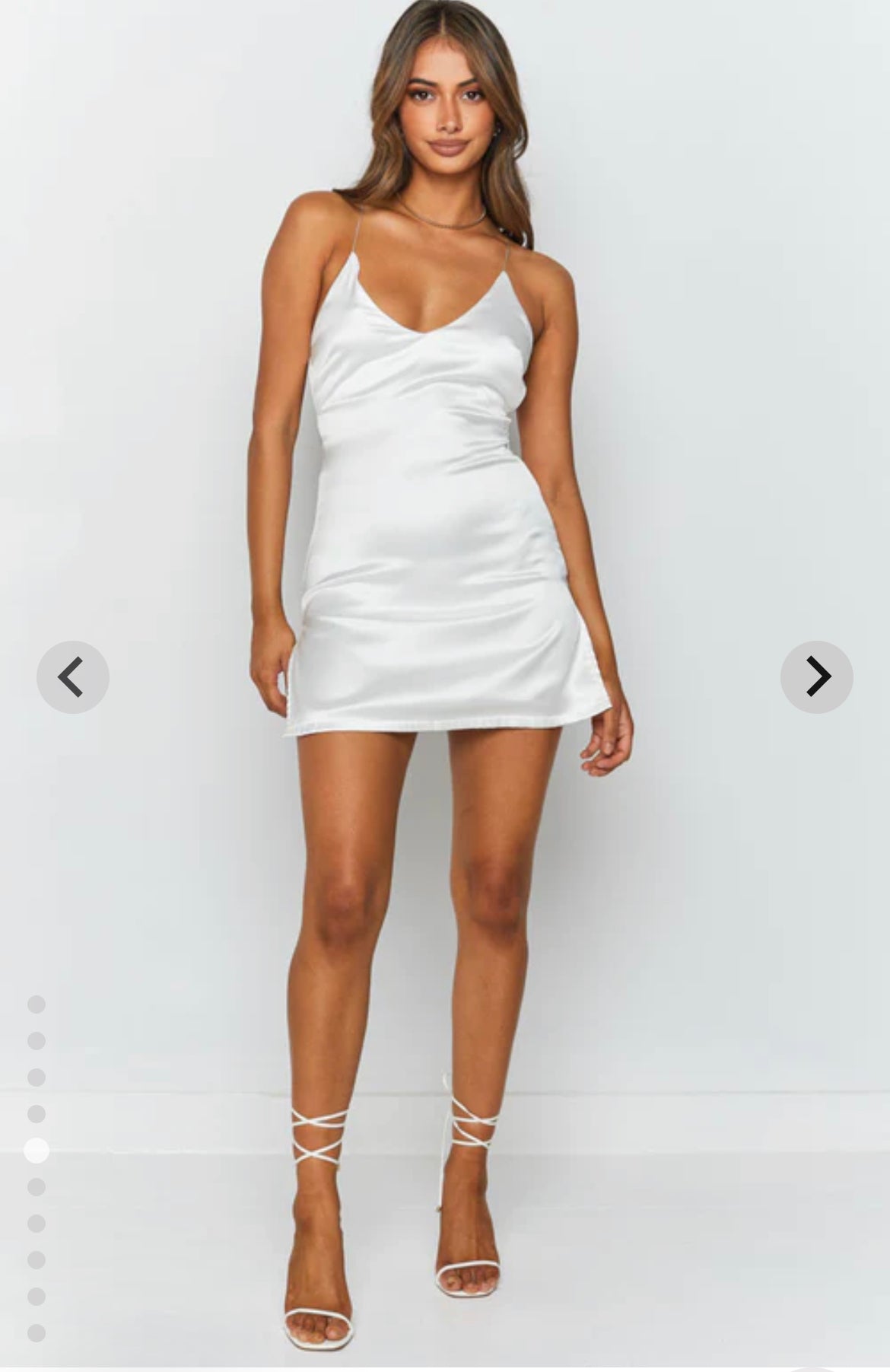 satin white mini dress for clubbing or party with tie up back and v neck . short dress. white strappy heels. front view